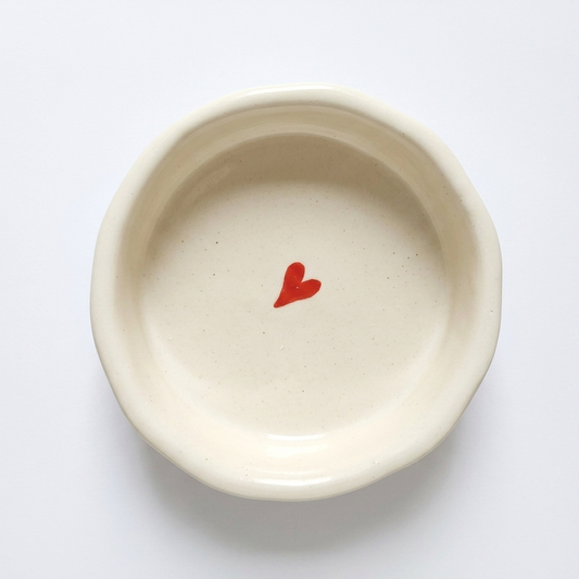 Small white bowl with a red heart on a white background