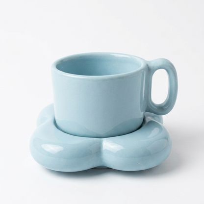 A light blue ceramic mug with a matching flower-shaped saucer, photographed on a clean white background.