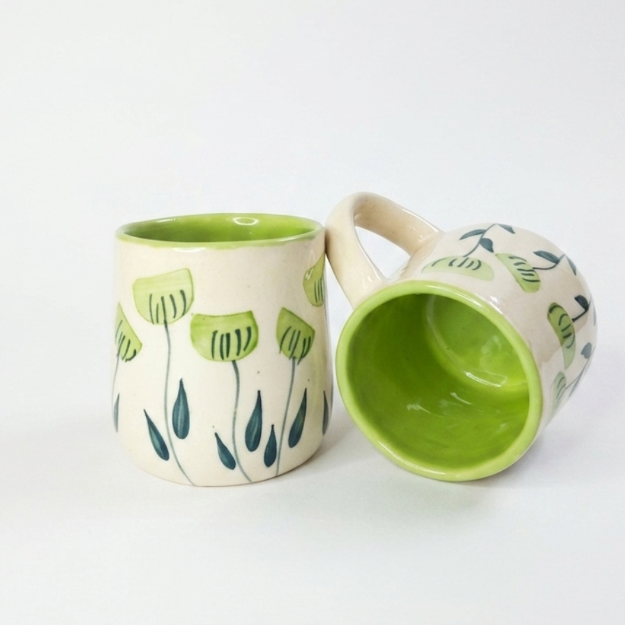 two green handpainted mugs in white background