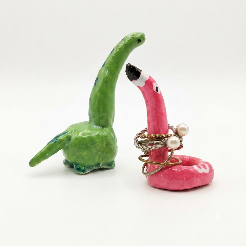 Green and pink dino and flamingo clay ring holder on a white background