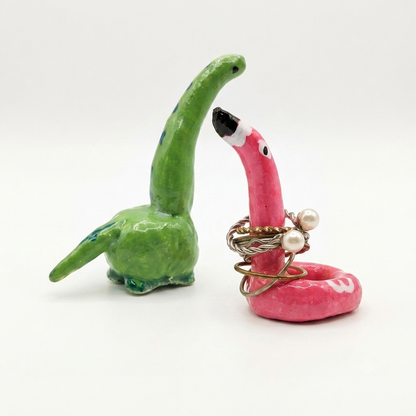 Green and pink dino and flamingo clay ring holder on a white background