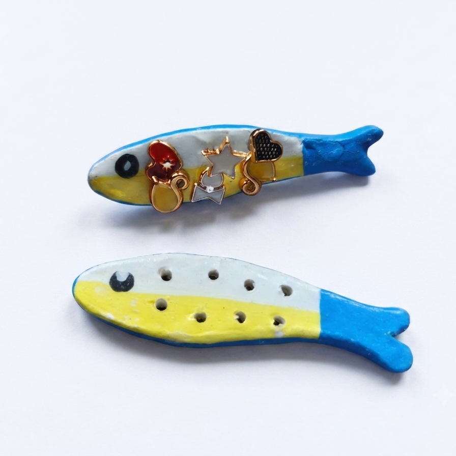 Two hand-painted fish-shaped earring holder on a white background, one with small gold charms and the other with ventilation holes.