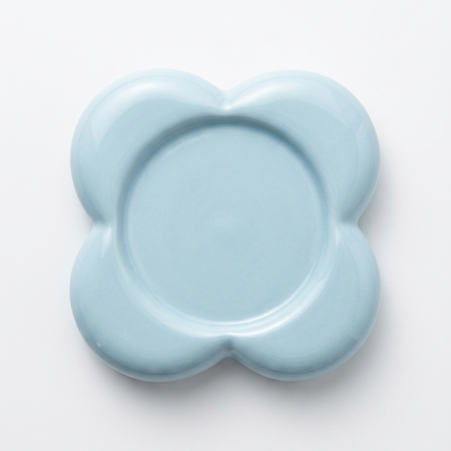 A light blue ceramic plate with a wavy, flower-like silhouette, photographed from directly above on a clean white background.