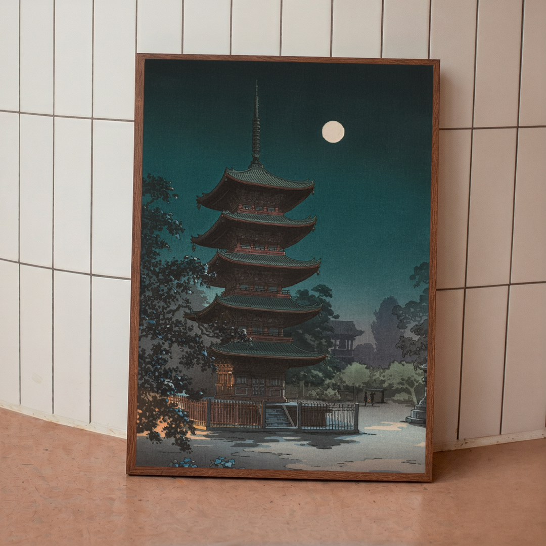 Framed artwork of a pagoda under a moonlit sky on a tiled wall.