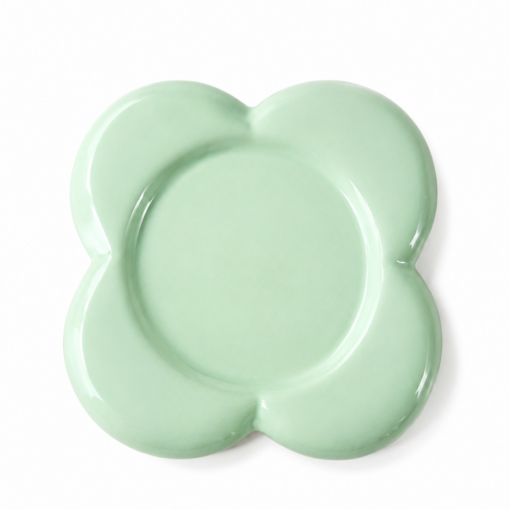 A mint green ceramic plate with a scalloped, flower-like border, photographed from directly above on a clean white background.