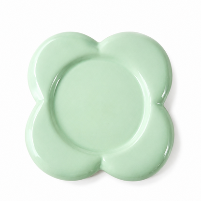 A mint green ceramic plate with a scalloped, flower-like border, photographed from directly above on a clean white background.