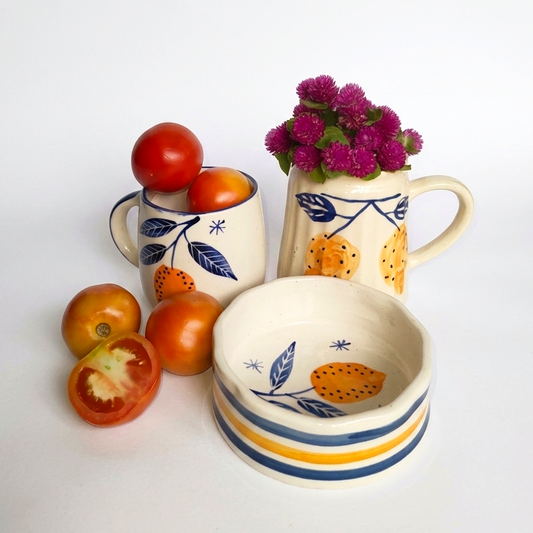 Ceramic items including a pitcher, cups, and a bowl with floral patterns on a white background.