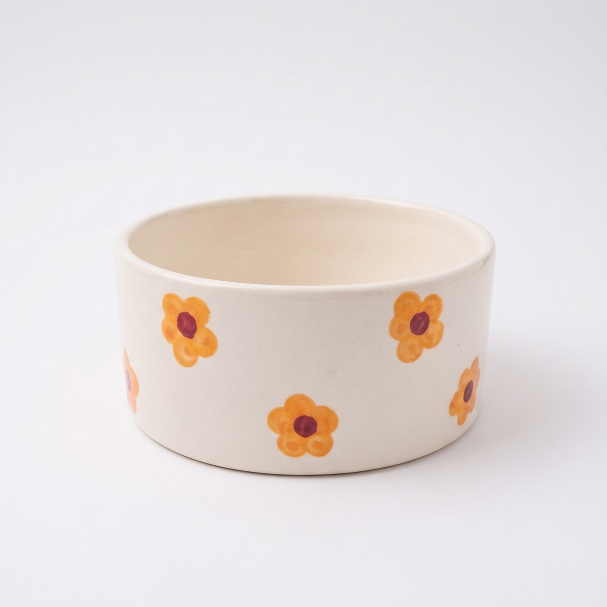 An off-white ceramic bowl decorated with a pattern of small orange flowers with dark red centers, set against a clean white background.