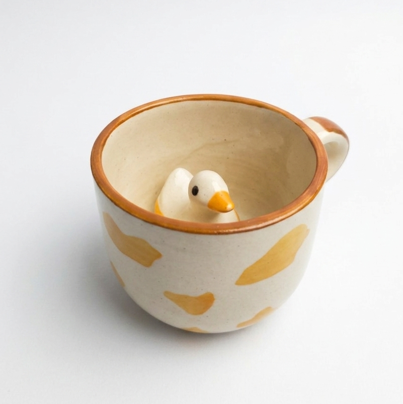 Ceramic cup with a duck peeking design on a white background