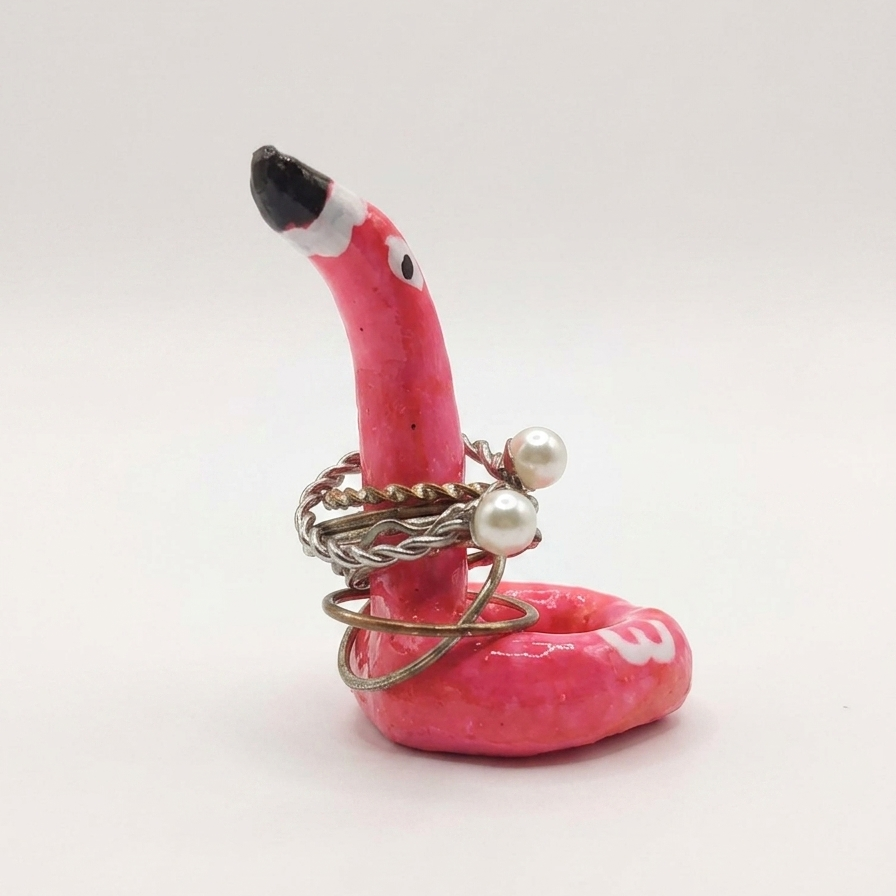 Pink flamingo ring holder with rings on a white background