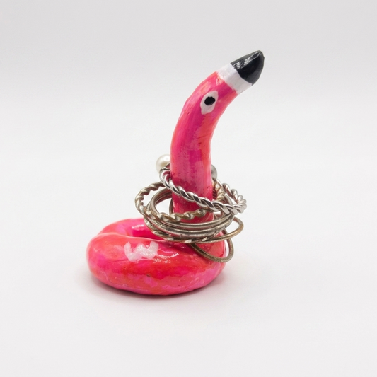 Pink flamingo ring holder with rings on a white background