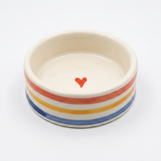 Ceramic bowl with rainbow stripes and a red heart on a white background
