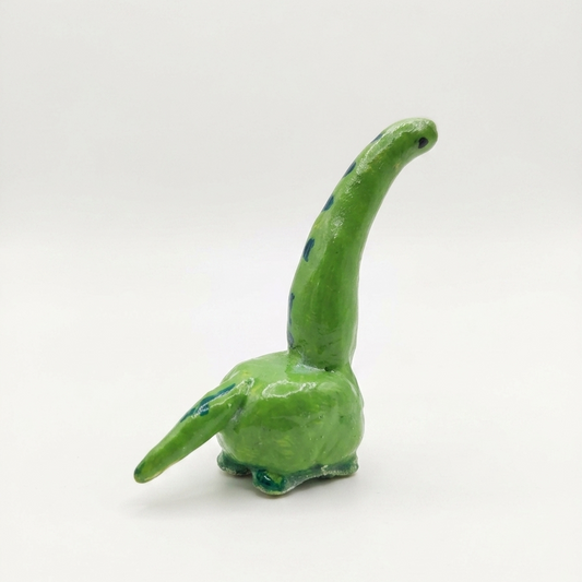 Green ceramic dinosaur figurine on a white background