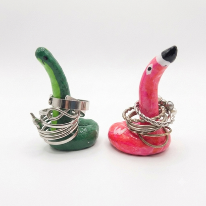 Two ring holders shaped like a green dino and pink flamingo with silver rings on a white background.