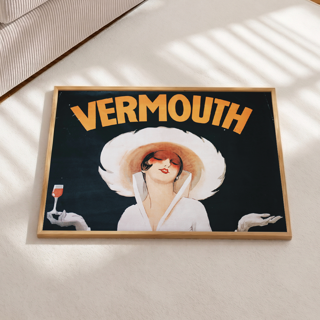 Vintage-style 'Vermouth' poster with a woman in a large hat on a light surface.